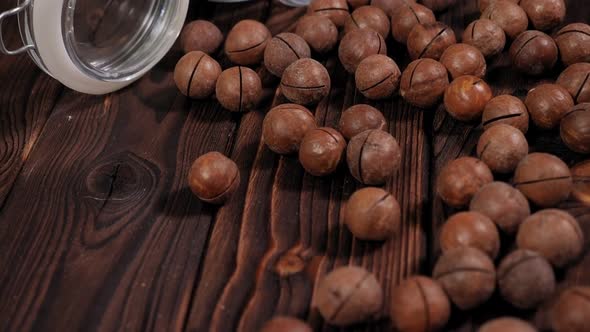 Closeup of Macadamia Nuts Scattered on a Wooden Brown Background