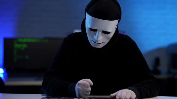 Nervous Stressed Unrecognizable Hacker in Black Clothes and Anonymous Mask Beating Table with Fists