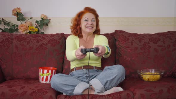 Retro Gamer Sitting on Couch with Game Controller Laughing Gesturing Having Fun