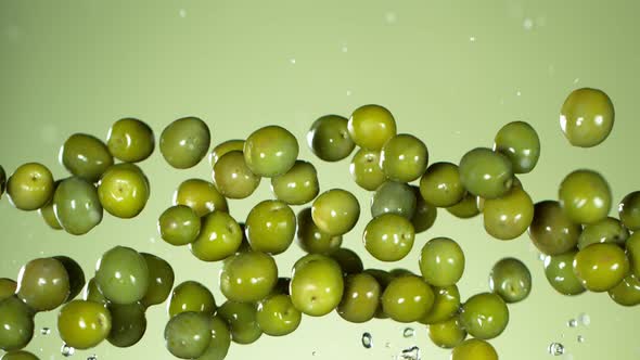 Super Slow Motion Shot of Flying Fresh Green Olives on Light Green Gradient Background at 1000 Fps