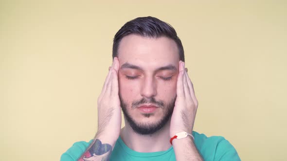 Young Man Suffering From Severe Headache Pressing Fingers to Temples Closing Eyes in Order to