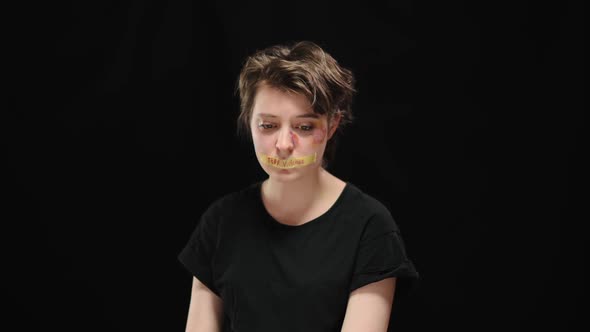 Frustrated Oppressed Caucasian Young Woman with Mouth Closed with Stop Violence Sign Looking at