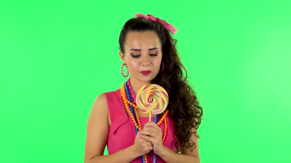 Girl with Great Pleasure Eats a Large Multi-colored Candy While Enjoying. Green Screen