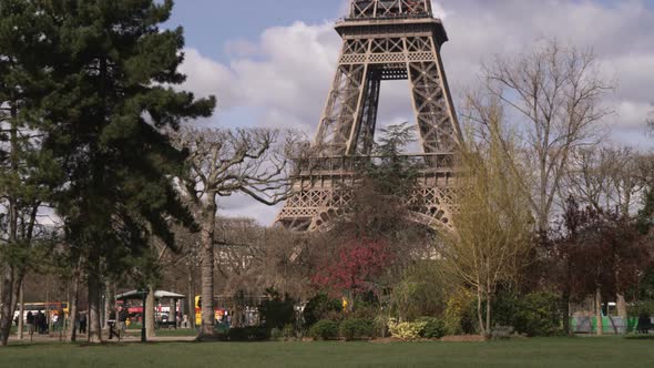 Base of the Eiffel Tower with trees and traffic.