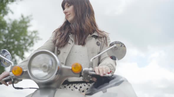 Young Caucasian Woman Sitting on Motorcycle Holding Steering Wheel. Portrait of Beautiful Smiling