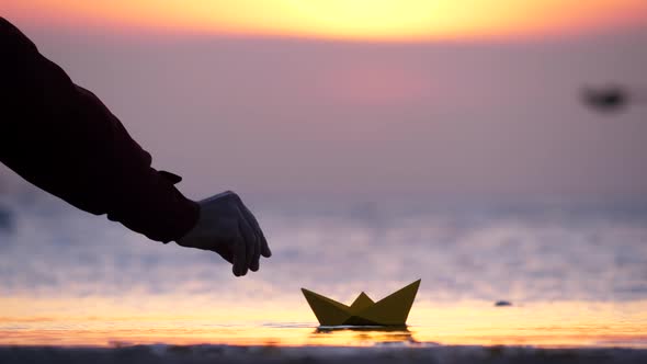 Man put paper ship on water and it quickly sail away, telephoto view