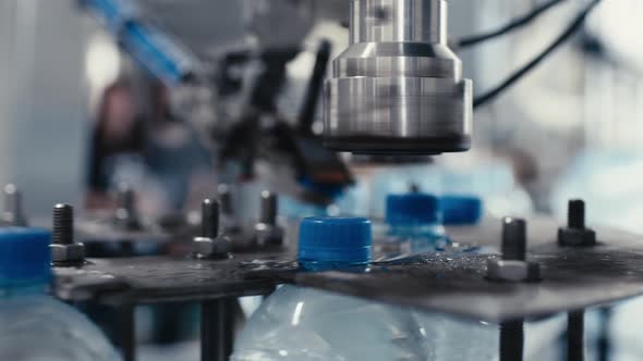 Water Factory Industrial Machine Puts Caps on Plastic PET Bottles with Water Close Up