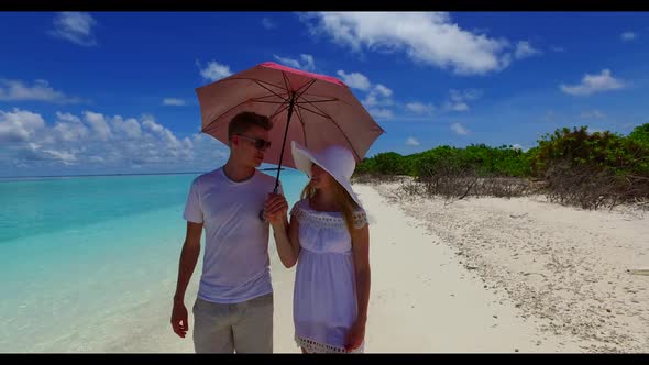 Young couple tan on relaxing lagoon beach trip by aqua blue lagoon with bright sand background of th