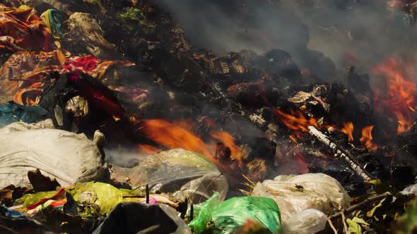 Close up shot of burning plastic trash with rising toxic fumes at sunny day