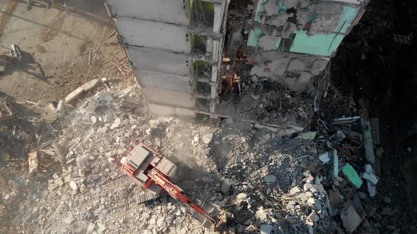 An Excavator Tractor Digs the Concrete Ruins of a Collapsed House with a Bucket