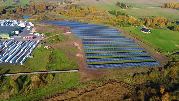 Aerial view of solar panel rows near a factory during Autumn, Estonia.