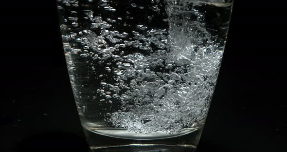 Water being poured into Glass against Black Background, Slow Motion 4K