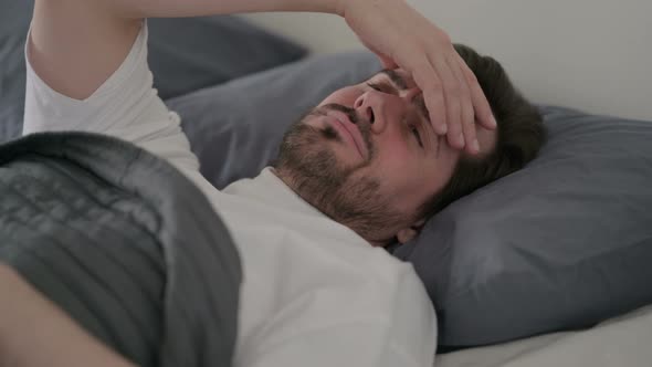 Young Man Having Headache While Sleeping in Bed