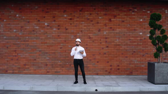 Wide Frame in Front of a Handsome Caucasian Worker with a Helmet, Standing Outdoors