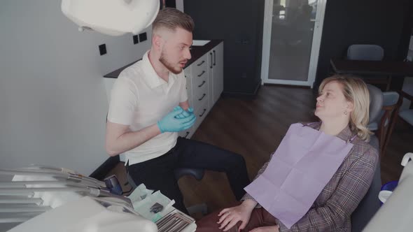 The male dentist explains to the patient the treatment plan at the dental clinic