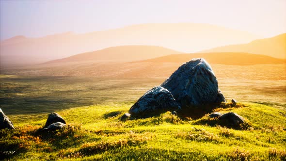 Meadow with Huge Stones Among the Grass on the Hillside at Sunset alt