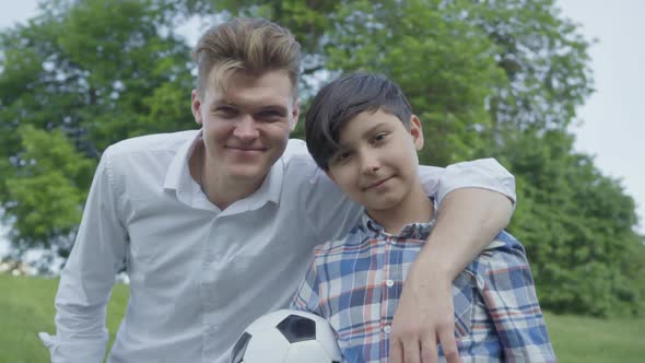 Portrait of a Young Father Hugging His Son. Joyful Smiling Boy Holding a Soccer Ball. Family Leisure