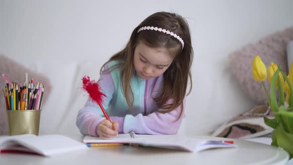 Glad Girl Doing Homework and Smiling