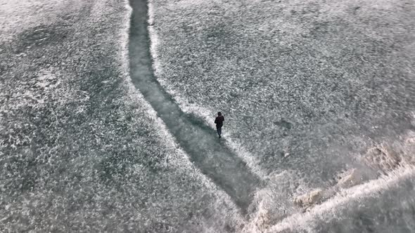 Aerial Birds Eye View Of Adult Male Walking Across Snow Covered Ground At Khalti Lake. Circle Dolly