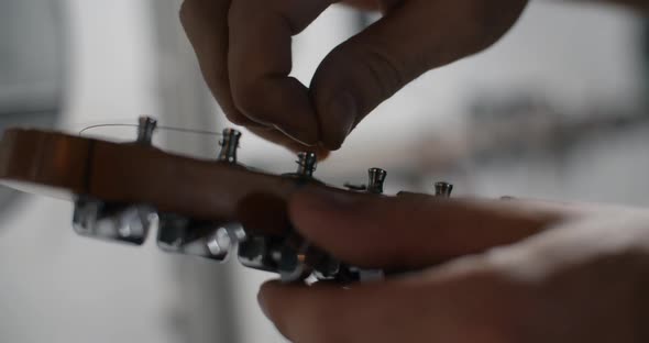 Guitar Tech Takes Off the Old Strings From the Guitar Tuners Changing the Strings on the Electric