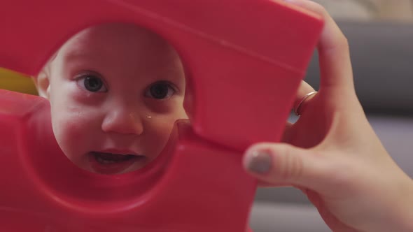 Funny Baby Toddler Boy Playing Red Toy Looking Into Hole Hiding Plastic Bricks