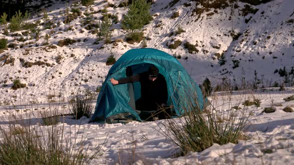 Hiker, arriving at tent, in the winter mountains