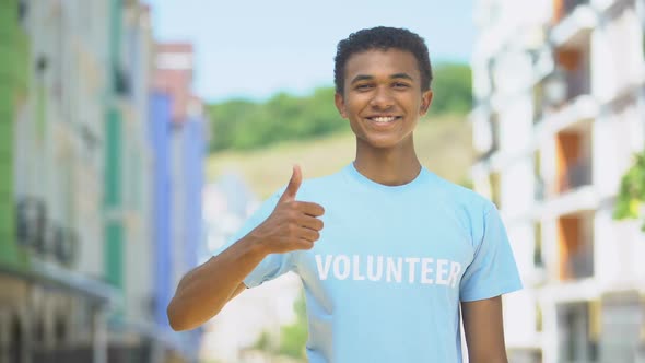 Merry Afro-American Teenager Volunteer Showing Thumbs-Up and Smiling on Camera