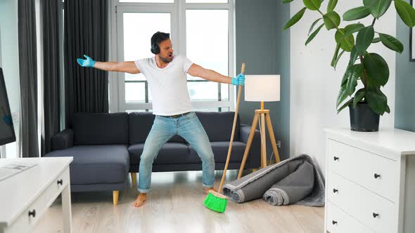 Man in Headphones Cleaning the House and Having Fun Dancing with a Broom