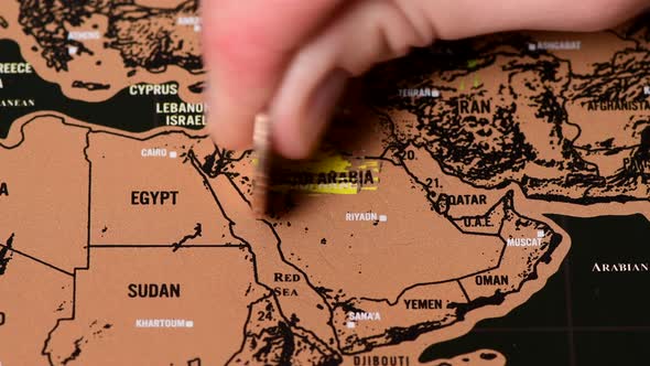 Person with One Dollar Coin Erase Black Scratch Travel Map of Saudi Arabia