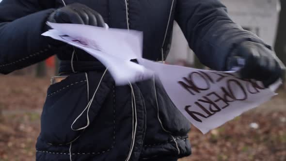 Unrecognizable Woman Tearing Placard Standing Outdoors on Autumn Spring Day