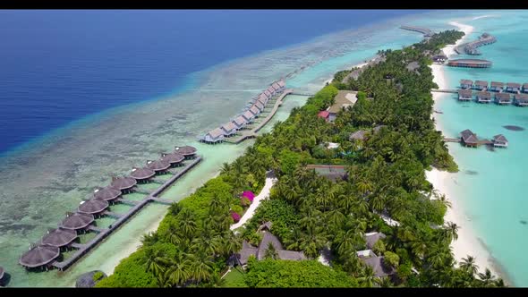 Aerial flying over landscape of exotic tourist beach vacation by blue ocean with white sand backgrou