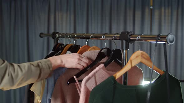 Close Up of Woman Takes a Pink Coat From a Hanger with Clothes