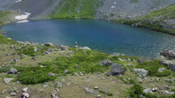 Aerial view. Woman standing near mountain emerald lake raising hands up Arkhyz North Caucasus nature