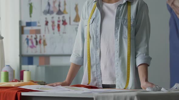 Female Atelier Owner Looking at Design Sketches of Evening Suits and Dresses