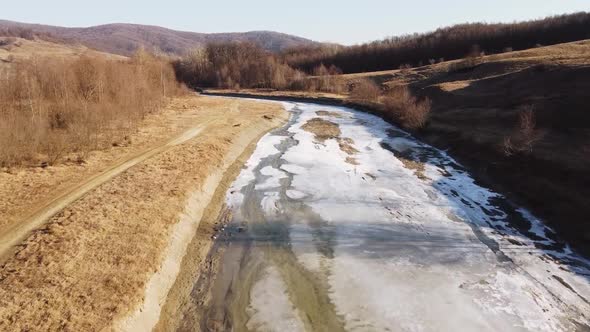 Drone shot of the forest and a country icy river in the late autumn. Late Autumn forest hills. Aeria