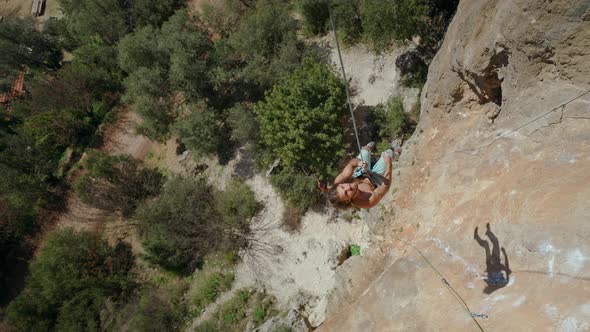 Slow Motion of Satisfied Handsome Muscular Man Rock Climber with Long Hair Hanging on Rope After