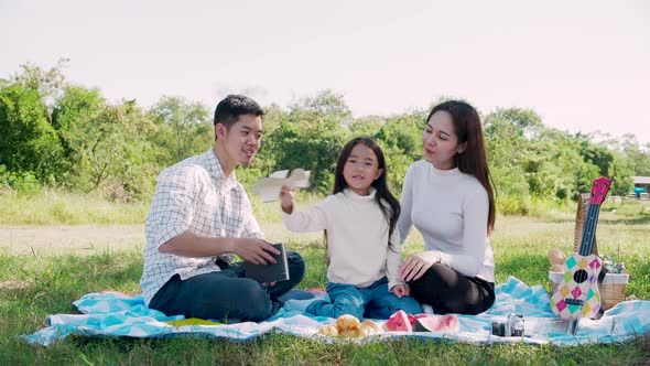 Asian parents and daughter playing the toy airplane and have enjoyed ourselves together while picnic