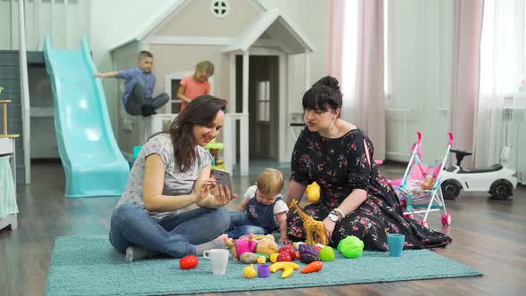 Female Friends Watching Photos Near Children