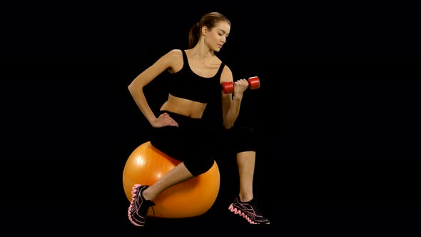 Girl Sitting on Pilates Ball and Exercising with Dumbbells. Alpha Channel.