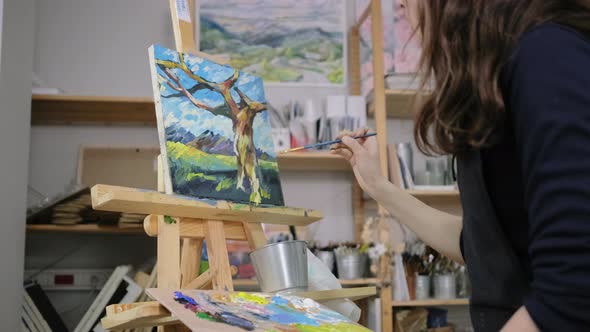 Paintress Is Depicting Tree Trunk on Picture with Landscape in Studio
