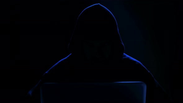 Unrecognizable Hacker in The Dark Works on The Computer