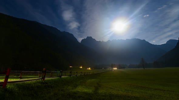 Timelapse of Alpine valley by night under full moon, illuminated farmhouse, cottage, full moon, clou alt