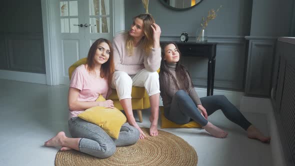 Three Attractive Girlfriends Sitting on the Sofa Talking Excitedly Smiling