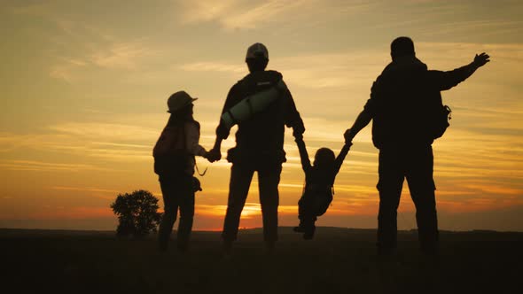 Parents and Two Children Walking in the Mountains at the Sunset Time. Silhouette