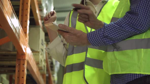 Closeup of the Hands of an Elderly Manager and a Young Employee with a Computer Tablet in a Vest