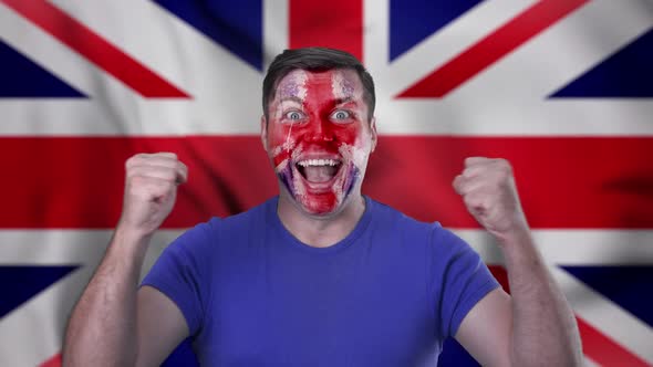 A screaming English football fan with a face painted in the color of England.