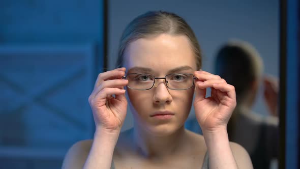 Upset Female Teenager Trying on Eyeglasses, Unsatisfied With Mirror Reflection