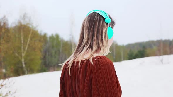 Style adult woman with headphones and burgundy color blouse on birch trees background. Spring time