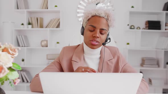 Young African American Woman in Wired Headset Using Laptop in Office