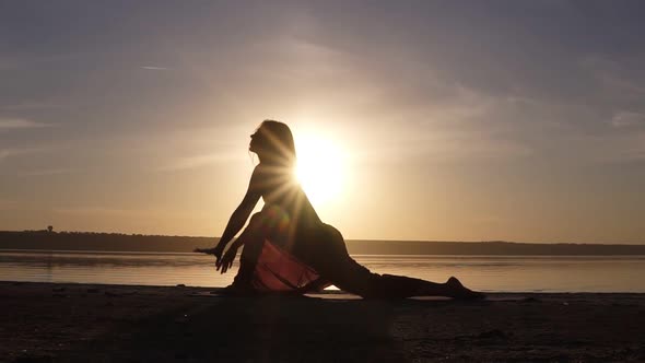 Silhouette of Beautiful Yoga Woman in the Morning Sky on a Sea Beach